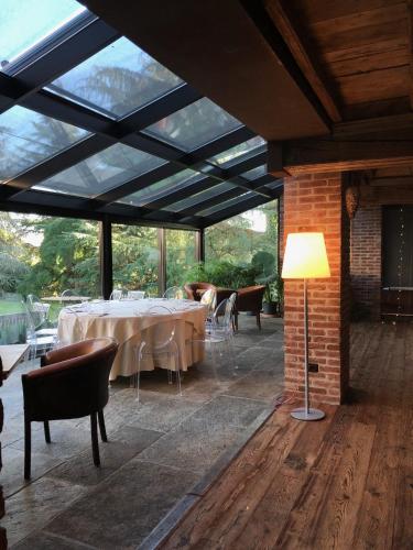 a dining room with tables and chairs and a lamp at Locanda Maison Verte in Cantalupa