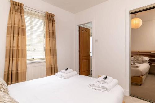 a bedroom with two white beds and a mirror at 2 Alexandra Court in St. Andrews