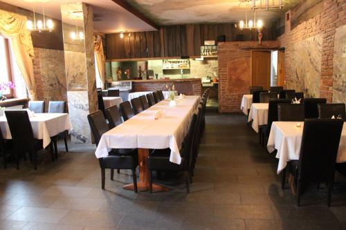 une salle à manger avec des tables blanches et des chaises noires dans l'établissement Hotel Młyn, à Lublin
