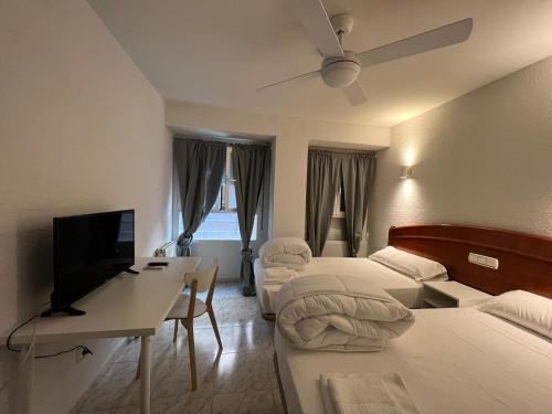 a hotel room with two beds and a television at Hostal la Embajada in Talavera de la Reina