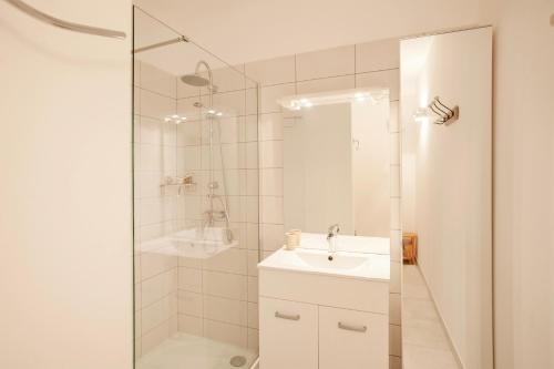 une salle de bain blanche avec une douche et un lavabo dans l'établissement Alivi - Appt climatisé avec vue mer et montagne, à LʼÎle-Rousse