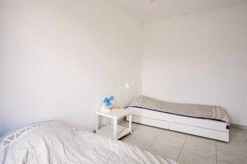 - une chambre blanche avec 2 lits une table de nuit dans l'établissement Alivi - Appt climatisé avec vue mer et montagne, à LʼÎle-Rousse