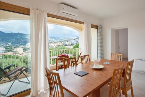 une salle à manger avec une table et des chaises et un balcon dans l'établissement Alivi - Appt climatisé avec vue mer et montagne, à LʼÎle-Rousse