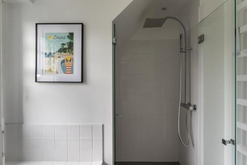 uma casa de banho com um chuveiro e uma imagem na parede em La Villa des Rochettes - Charmante maison avec piscine et jardin em Dinard