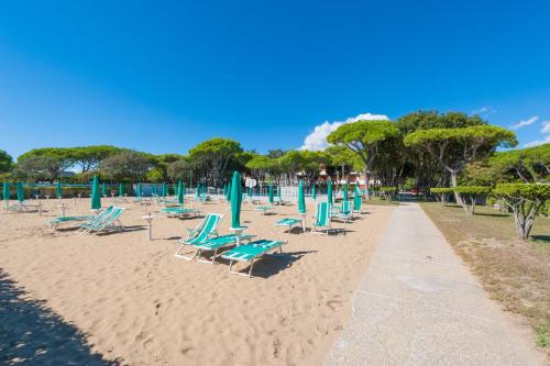 una playa de arena con sillas y sombrillas. en Park Residence Immobiliare Pacella en Lido di Jesolo