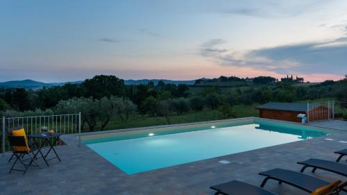a swimming pool with chairs and a table on a patio at CASA LA FENICE 8&2, Emma Villas in Pomarance