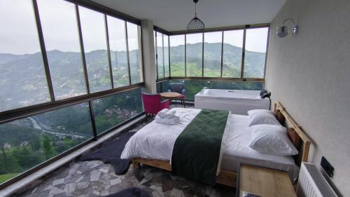 een slaapkamer met een bed in een kamer met grote ramen bij Burahan Suit Hotel in Çamlıhemşin