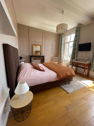 a bedroom with a bed and a table with a lamp at Le Logis d’Anne-Sophie in Chuignolles