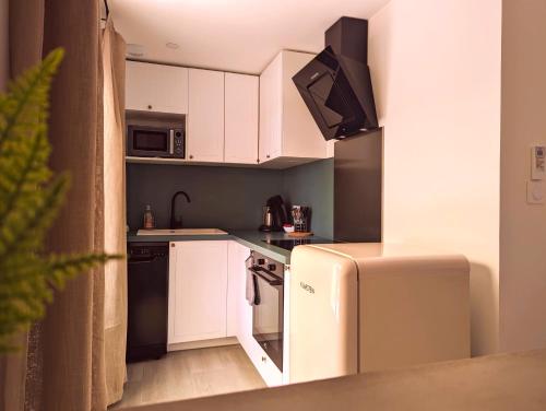 a small kitchen with white cabinets and a refrigerator at Litchi in Canet-en-Roussillon