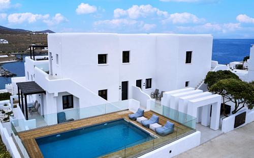 a white house with a swimming pool and the ocean at The Thermia Suites in Kithnos