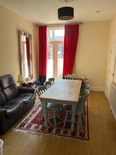 sala de estar con mesa y cortinas rojas en Number 33 Family Beach Residence en Great Yarmouth