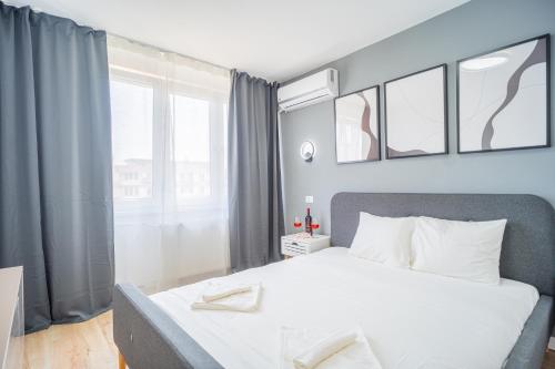 een slaapkamer met een bed en een groot raam bij Refreshingly Chic: Newly Renovated 2BR Apartment in Boekarest