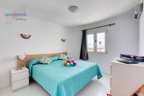 a bedroom with a bed with blue sheets and a window at Vivienda Vacacional Las Coronas 48 in Costa Teguise