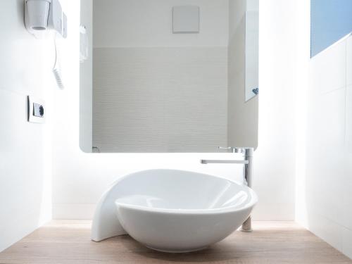 a white bathroom with a large white bowl sink at Hotel Almazzago in Commezzadura