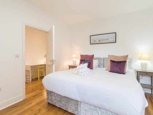 a bedroom with a large white bed with purple pillows at Pass the Keys Chic 1 Bed Flat in Quaint Sunninghill Village in Ascot