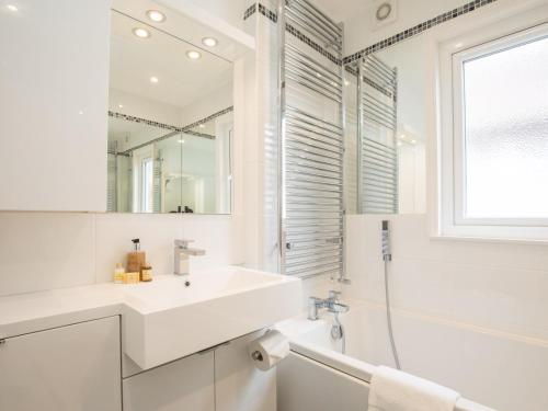 La salle de bains blanche est pourvue d'un lavabo et d'un miroir. dans l'établissement Pass the Keys Chic 1 Bed Flat in Quaint Sunninghill Village, à Ascot
