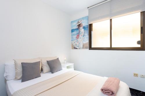 a white bedroom with a large bed and a window at Home2Book Percy Apartment El Médano Beach in El Médano