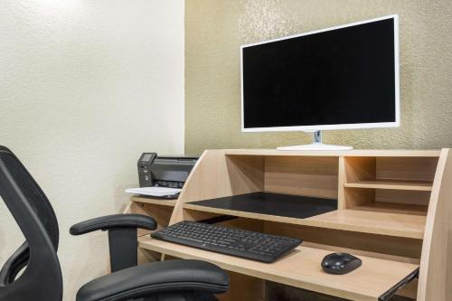 a desk with a computer monitor and a keyboard and mouse at Travelodge by Wyndham Juneau in Mendenhaven
