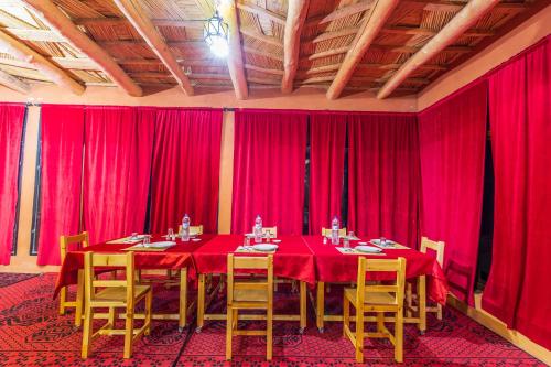 a dining room with red curtains and tables and chairs at Palais Ksar Lamane in Aït Ben Haddou