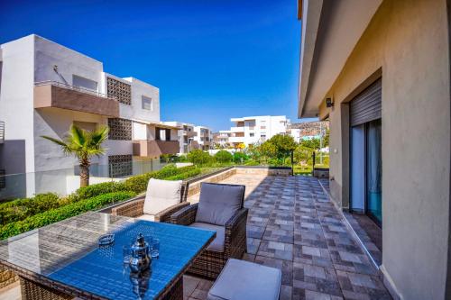 d'une terrasse avec une table en verre et des chaises sur un balcon. dans l'établissement Aladdin - Lunja - Luxe - piscines - 6 Px, à Agadir nʼ Aït Sa