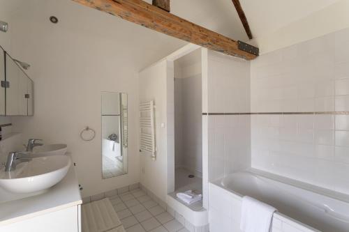 une salle de bain blanche avec une baignoire et un lavabo dans l'établissement L'Ecrin du Val - Charmante maison pour 6 et jardin, à Saint-Malo