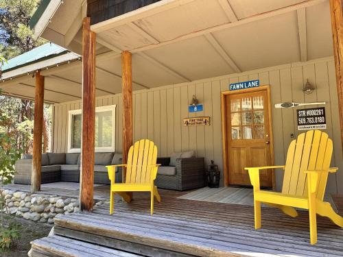 two yellow chairs on a porch of a house at Pine Tree Cottage by NW Comfy Cabins in Leavenworth