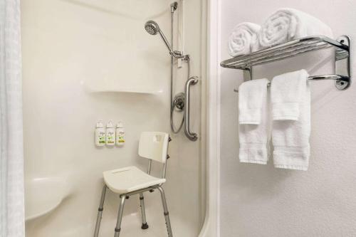 a bathroom with a shower and a stool and towels at Ramada by Wyndham Helena in Helena