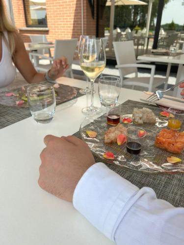 a person sitting at a table with a plate of food and wine at Hotel Gardenia Fiera in Cermenate