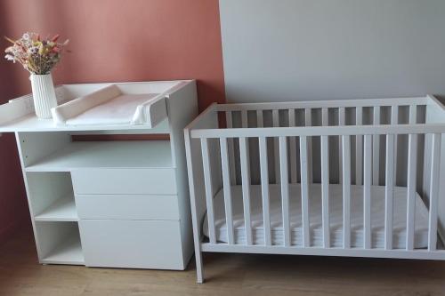 un lit bébé et une table avec un vase de fleurs dans l'établissement Superbe maison familiale à 50 m de la plage, à Concarneau