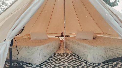 dwa łóżka w płóciennym namiocie ze stołem w obiekcie Rustika Glamping w mieście Kampong Tanjong Che Lahom