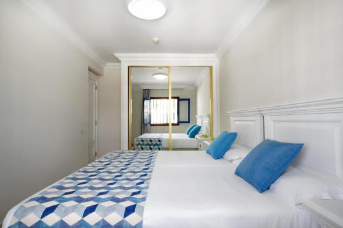 een slaapkamer met een groot wit bed met blauwe kussens bij Labranda Los Cocoteros in Puerto del Carmen