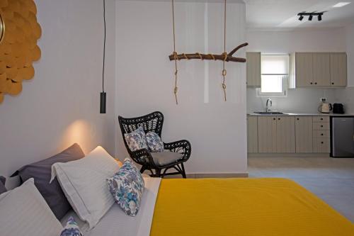 a bedroom with a bed and a chair and a kitchen at Alko Apartments in Mýkonos City