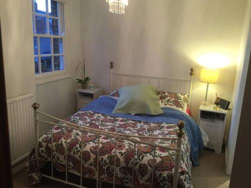 a bedroom with a bed with a blanket and a window at Bell Hay House in Glastonbury