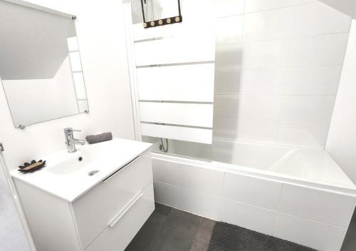 a white bathroom with a sink and a bath tub at "Colbert Triplex" 3 chambres - Balcon - Patio - Cathédrale in Tours