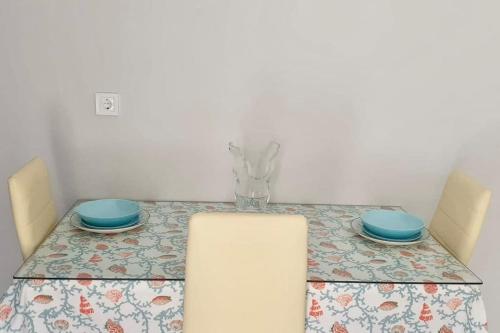 a table with two blue plates and a vase on it at Handra Apartment Seaview in Kos Town