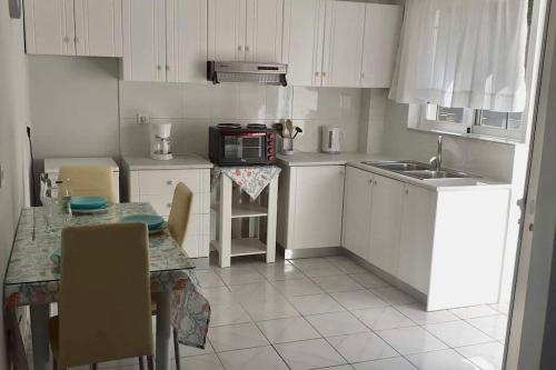 a small kitchen with white cabinets and a table with chairs at Handra Apartment Seaview in Kos Town