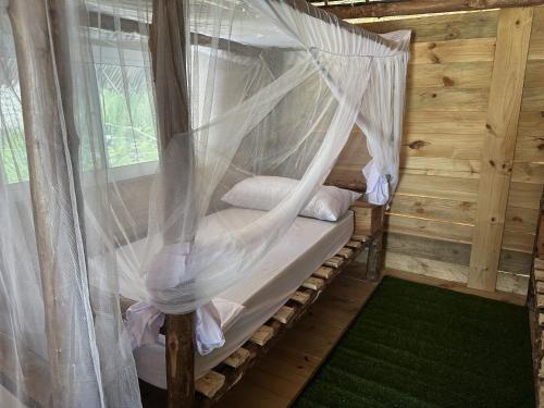 a bed in a wooden room with mosquito nets at Coconuts Bandas in Jambiani