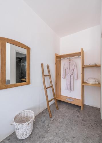 a dressing room with a mirror and a suit on a wall at Anita Rooms & Suites Milos in Adamas