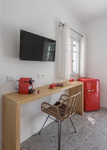 a desk with a television and a chair in a room at Anita Rooms & Suites Milos in Adamas