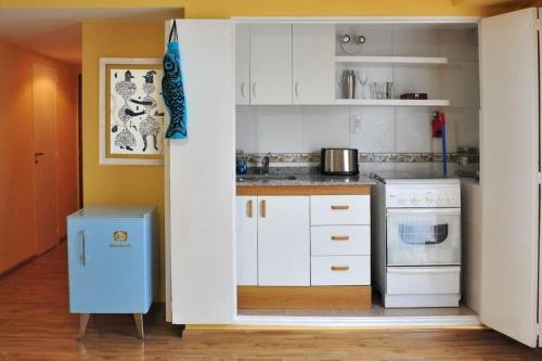 a kitchen with white cabinets and a blue trash can at Sweet and Little Home in Buenos Aires