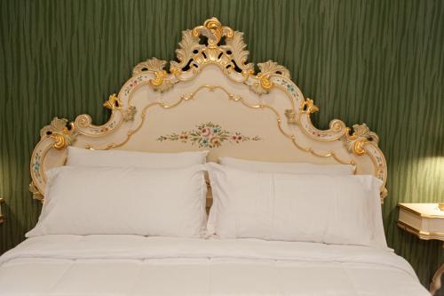 a white bed with an ornate headboard and white pillows at Residenza Catullo in Verona
