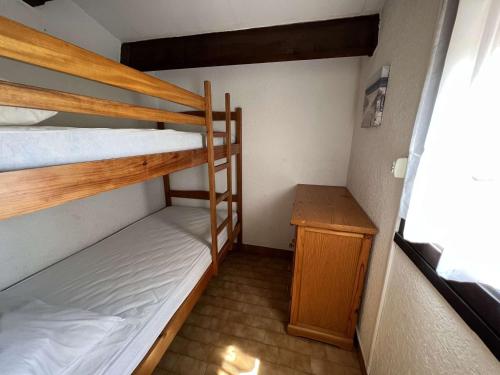 Cette petite chambre comprend 2 lits superposés et une table en bois. dans l'établissement Appartement 3 Pièces, Cabine, Proche Plage Richelieu, Parking, Wifi, Animaux Acceptés - FR-1-702-61, au Cap d'Agde