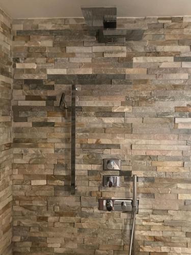 uma parede de tijolos na casa de banho com um chuveiro em Les oliviers em Rolle