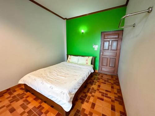 a small bedroom with a green wall and a bed at Chatchawan Resort in Ban Tha Sao