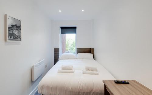 a white bedroom with a large bed and a table at Liverpool Short Stay Apartments in Liverpool