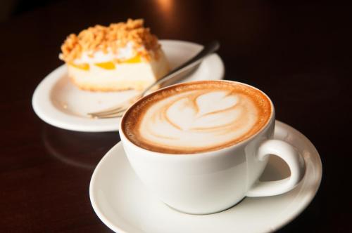a cup of coffee next to a piece of cake at Hotel Panorama Nowy Sącz in Nowy Sącz