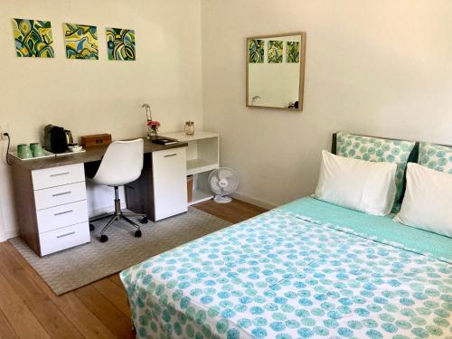 1 dormitorio con cama, escritorio y silla en Les oliviers, en Rolle