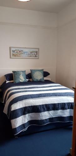 Una cama con una manta de rayas azul y blanca. en Rose Court Holiday Apartments en Torquay