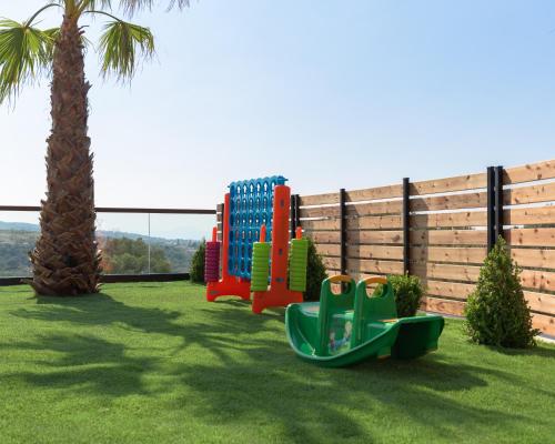 a playground with a slide and a palm tree at Villa En Paraiso a Majestic SeaView Retreat By ThinkVilla in Giannoudi