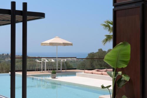 a view of a swimming pool with an umbrella at Villa En Paraiso a Majestic SeaView Retreat By ThinkVilla in Giannoudi
